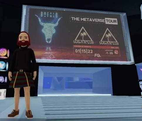 A bearded Avatar in the center of Decentraland in front of the Metaverse Tour Billboard.