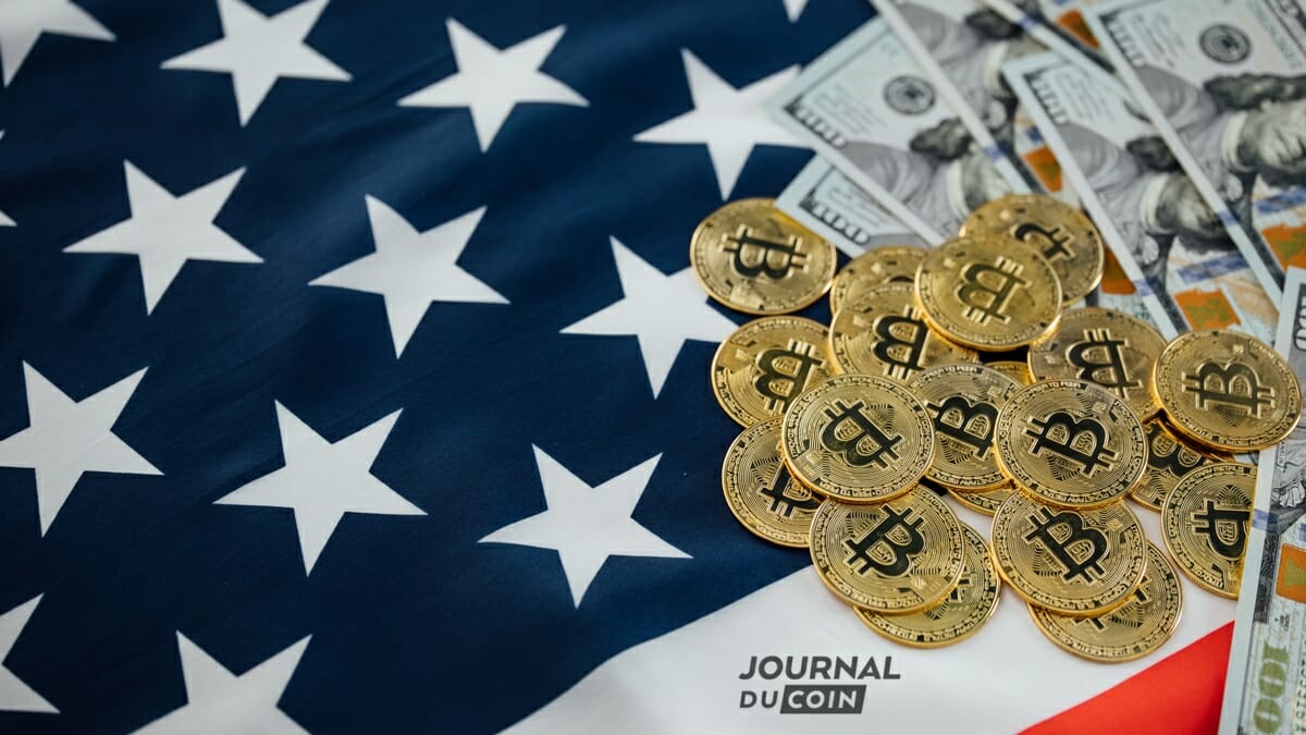 Ce drapeau des USA avec un tas de billets de dollars et de pièces de bitcoins symbolise ici les attaques de la régulation contre les cryptomonnaies pour protéger son dollar et renflouer ses caisses